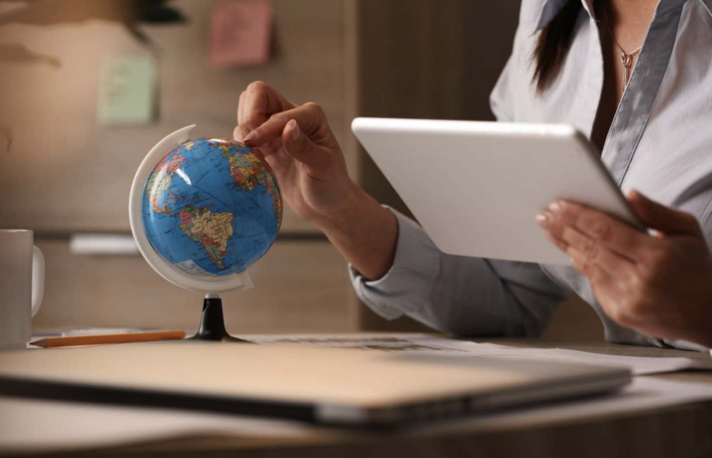 A businesswoman using a digital tablet while examining the globe